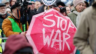 Participants à la manifestation devant la porte de Brandebourg avec un parapluie "Stop War" (Photo : imago images/Jean MW)